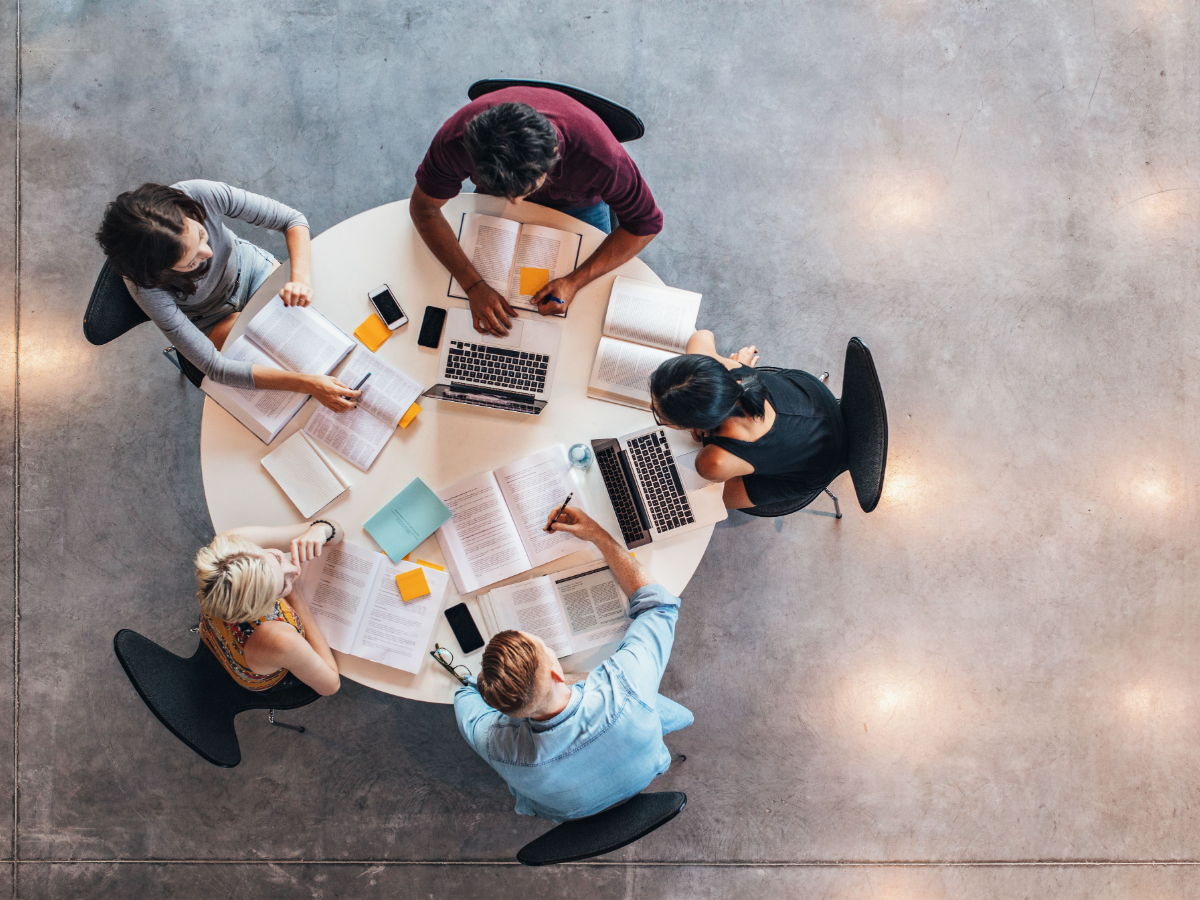 Students at a table reading and working on their laptops